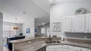 A modern kitchen with granite countertops, white cabinetry, and stainless steel appliances.