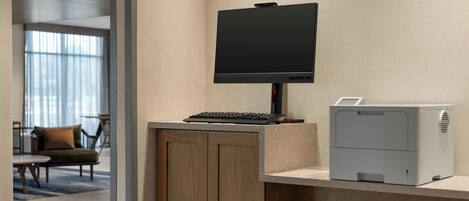 A reception desk with a flat-screen monitor, a keyboard, and a printer.