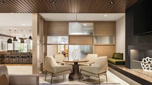 A modern interior with a round table and chairs, a sofa, and a kitchen area in the background. - Fairfield Inn & Suites by Marriott® Bethlehem Lehigh (Bethlehem)