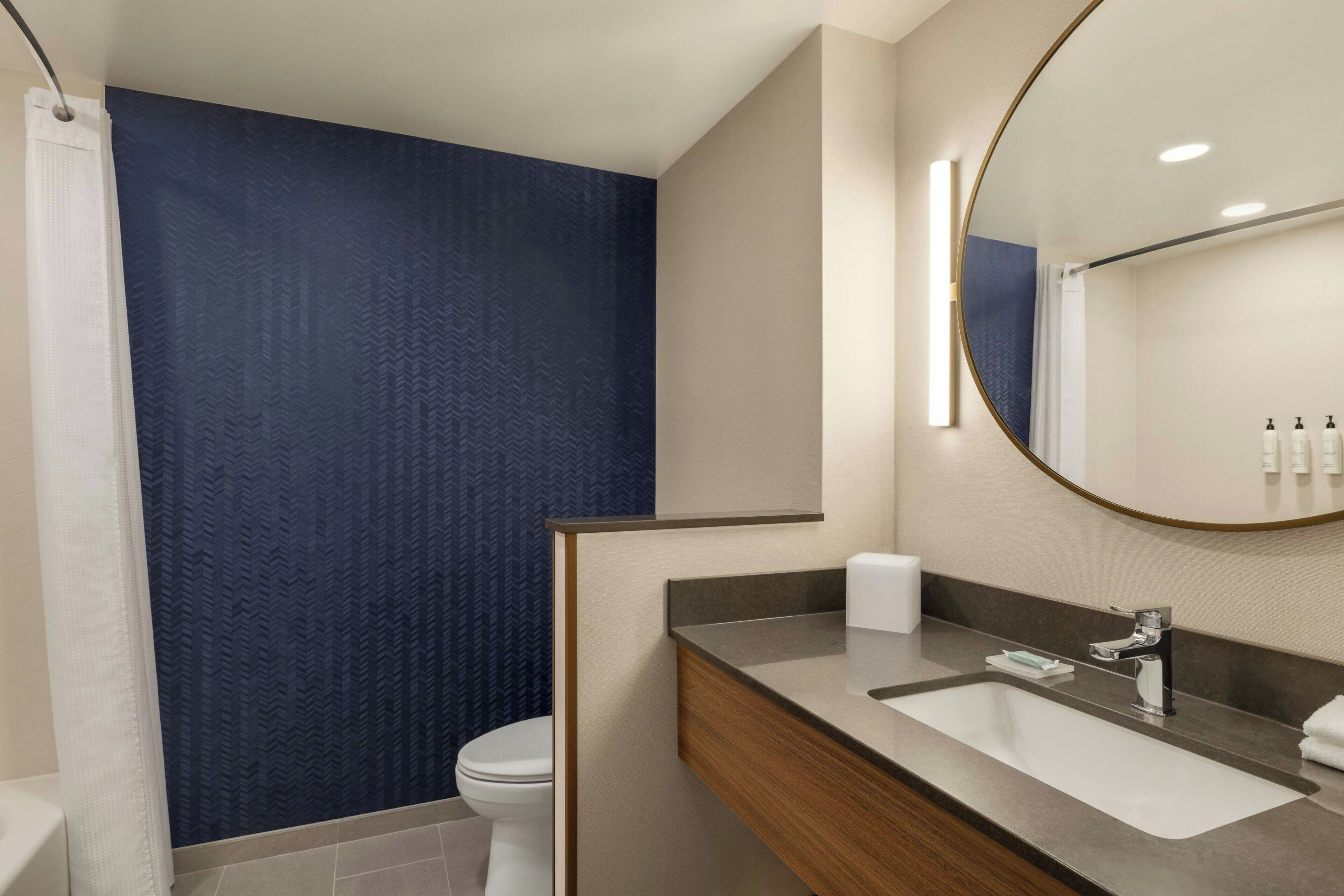 A modern bathroom with a large mirror, a sink, and a toilet.