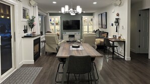 A modern dining area with a wooden table and chairs, a built-in oven, and a flat-screen TV. - The View on 87th Osoyoos 2 bedroom, 1.5 bath, covered patio view vacation home. (Osoyoos)