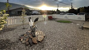 A gravel patio with a decorative rock arrangement and a white picket fence. - The View on 87th Osoyoos 2 bedroom, 1.5 bath, covered patio view vacation home. (Osoyoos)