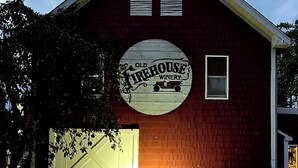 Un edificio rojo con una puerta de garaje y un letrero que dice "Old Firehouse Winery".