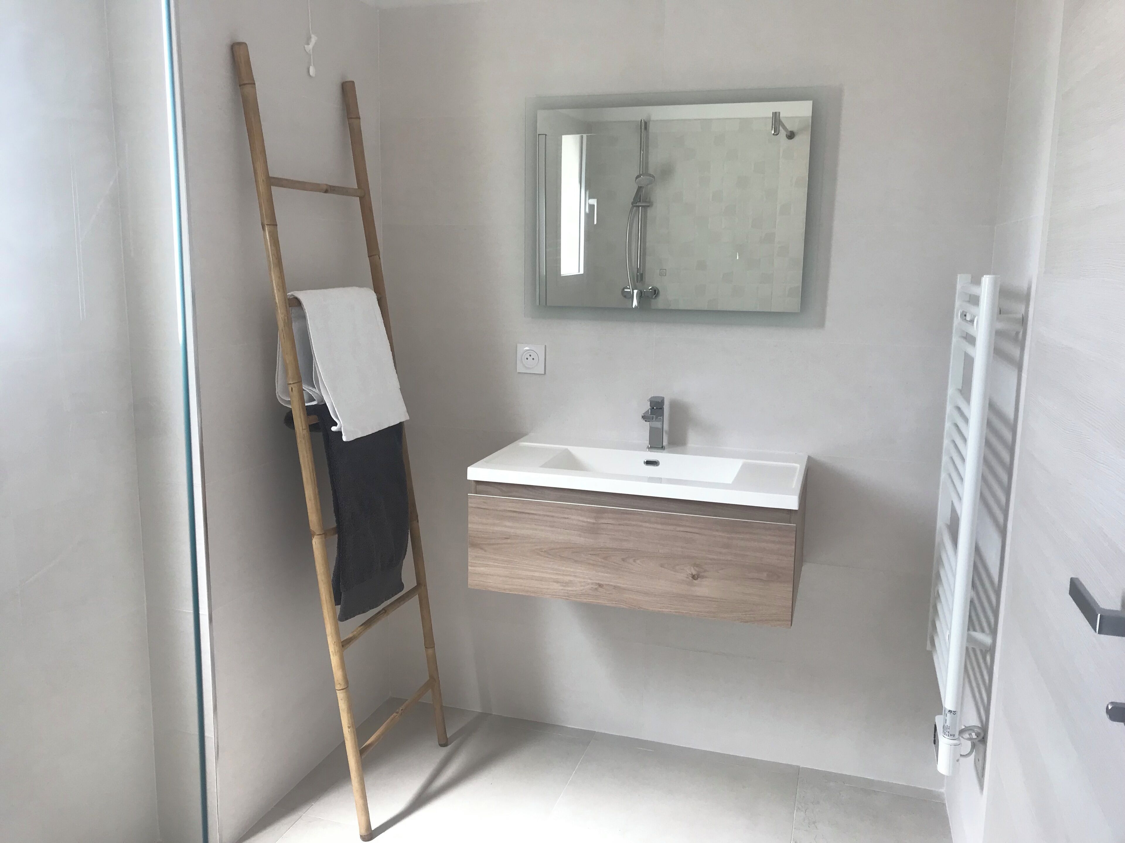 Une salle de bain avec une échelle en bois, un lavabo blanc et un miroir au-dessus.