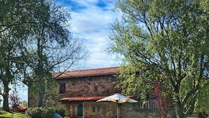 A stone building with a red-tiled roof, surrounded by lush green grass and trees. - Country House 'La Casa Del Chileno' with Sea View, Private Terrace and Private Garden (Lierganes)