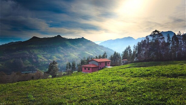 Une maison située sur une colline, offrant une vue sur les montagnes.