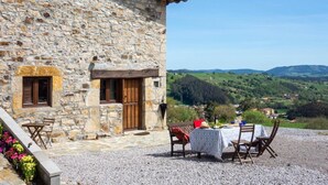 Un bâtiment en pierre doté d’une terrasse, de sièges en plein air et offrant une vue panoramique.