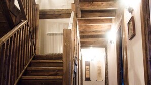Un escalier en bois mène à une pièce où se trouve un radiateur et, au mur, un cadre contenant une œuvre de calligraphie.