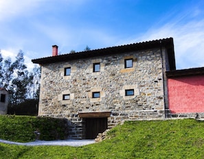Un edificio de piedra con techo rojo, una puerta de madera y una pequeña escalera que lleva a la entrada.
