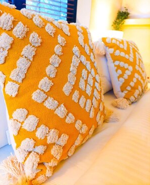 A bed with a yellow pillow featuring a textured pattern and a white pillow with a similar design. - Perfect sunny Studio in the city- Broadway- Chippendale (Chippendale)