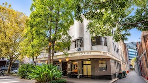 A building with a curved facade, signage for cocktails, food, and craft beer, and a street view with trees and parked cars. - Perfect sunny Studio in the city- Broadway- Chippendale (Chippendale)
