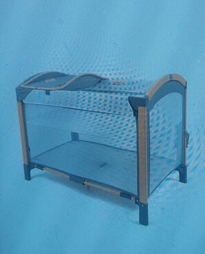 A metal-framed, open-top baby crib with a mesh top, set against a blue textured wall. - Perfect sunny Studio in the city- Broadway- Chippendale (Chippendale)