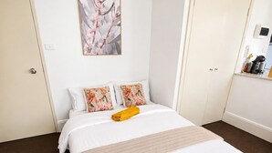 A hotel room with a bed, a painting on the wall, and a kitchenette area. - Perfect sunny Studio in the city- Broadway- Chippendale (Chippendale)