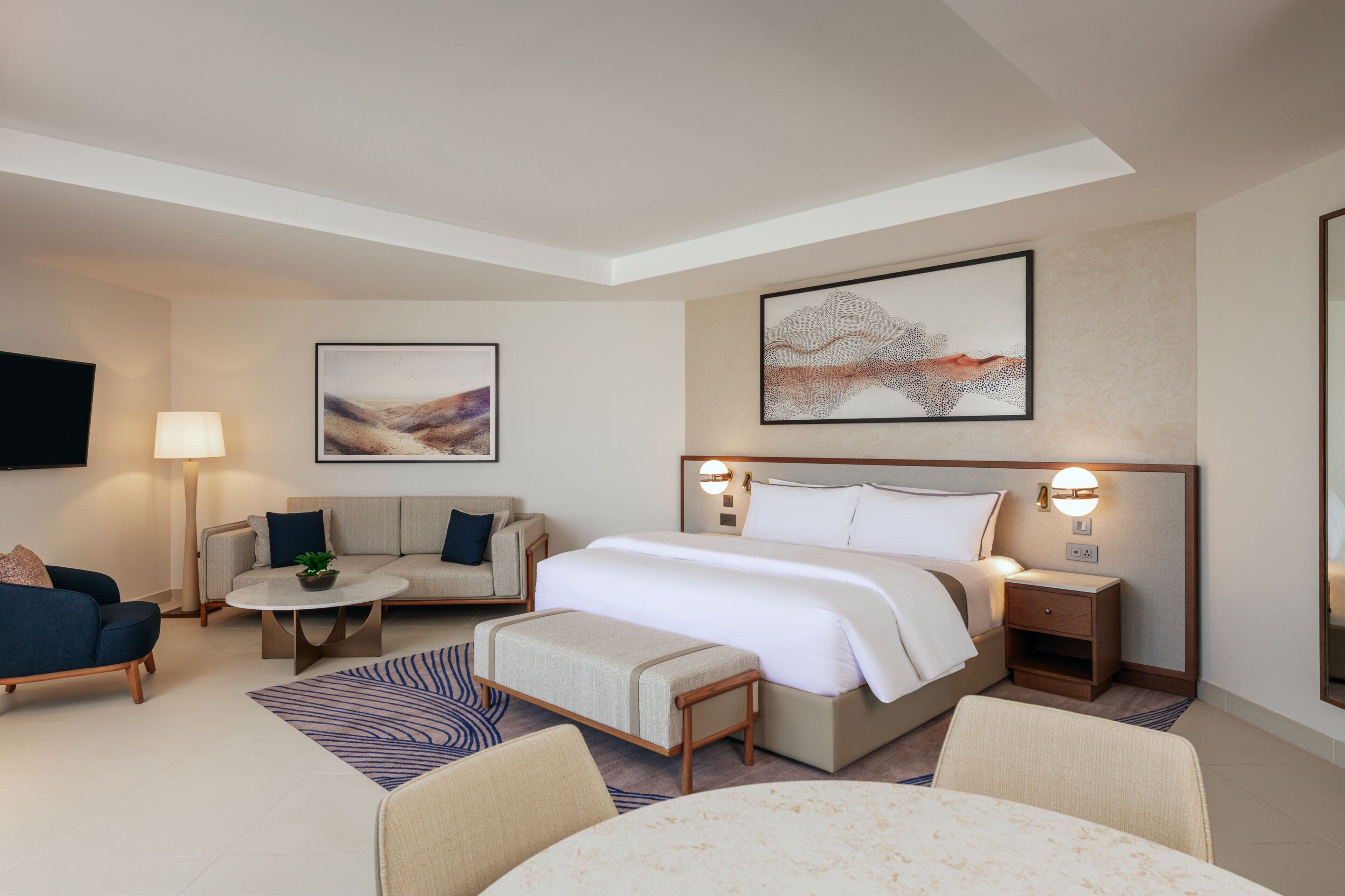 Una habitación de hotel con una cama, un sofá, una mesa de centro y una televisión.