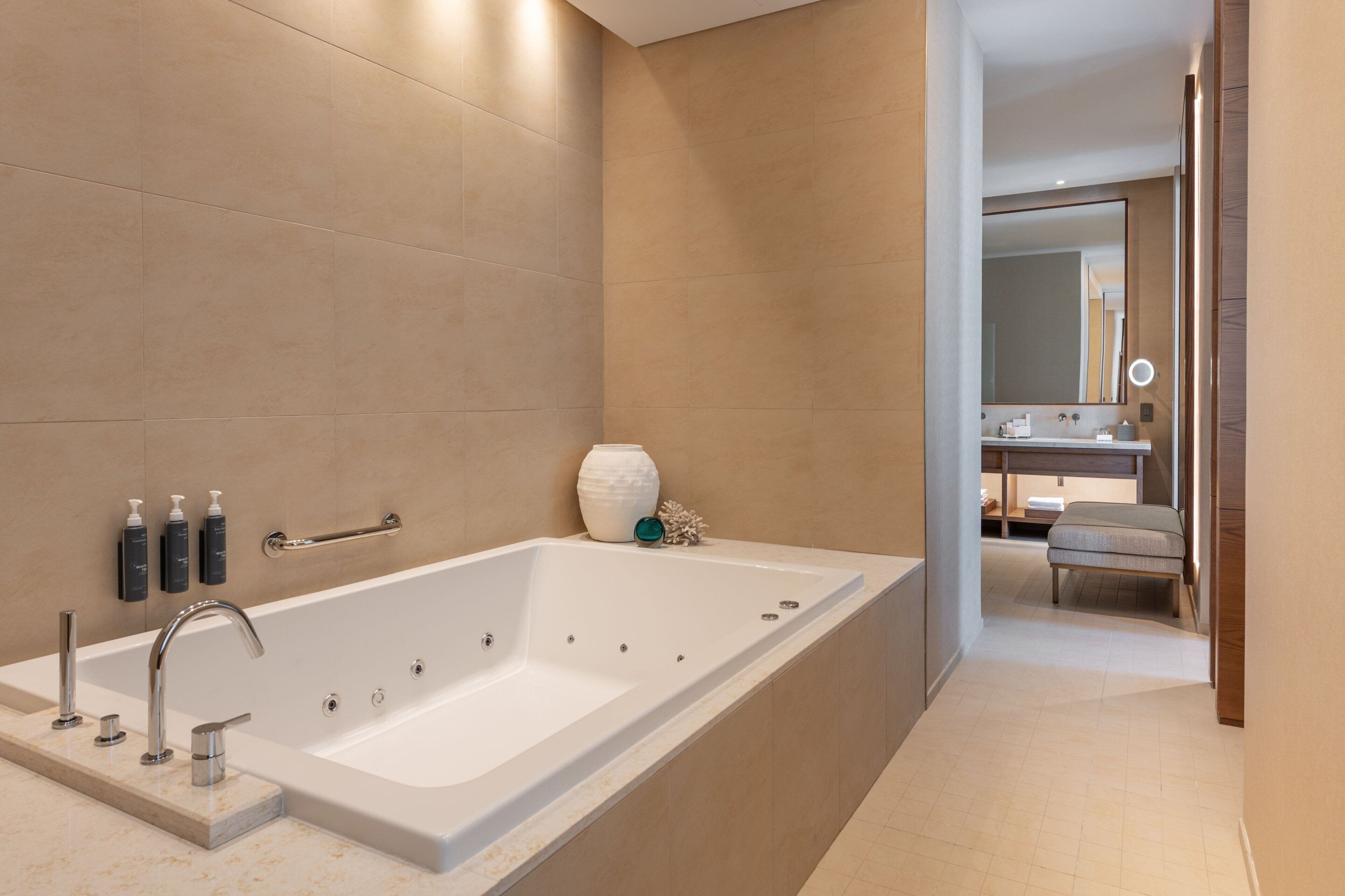 A modern bathroom with a large bathtub, a vanity with a mirror, and a toilet.