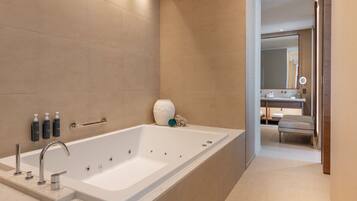 A modern bathroom with a large bathtub, a vanity with a mirror, and a toilet.