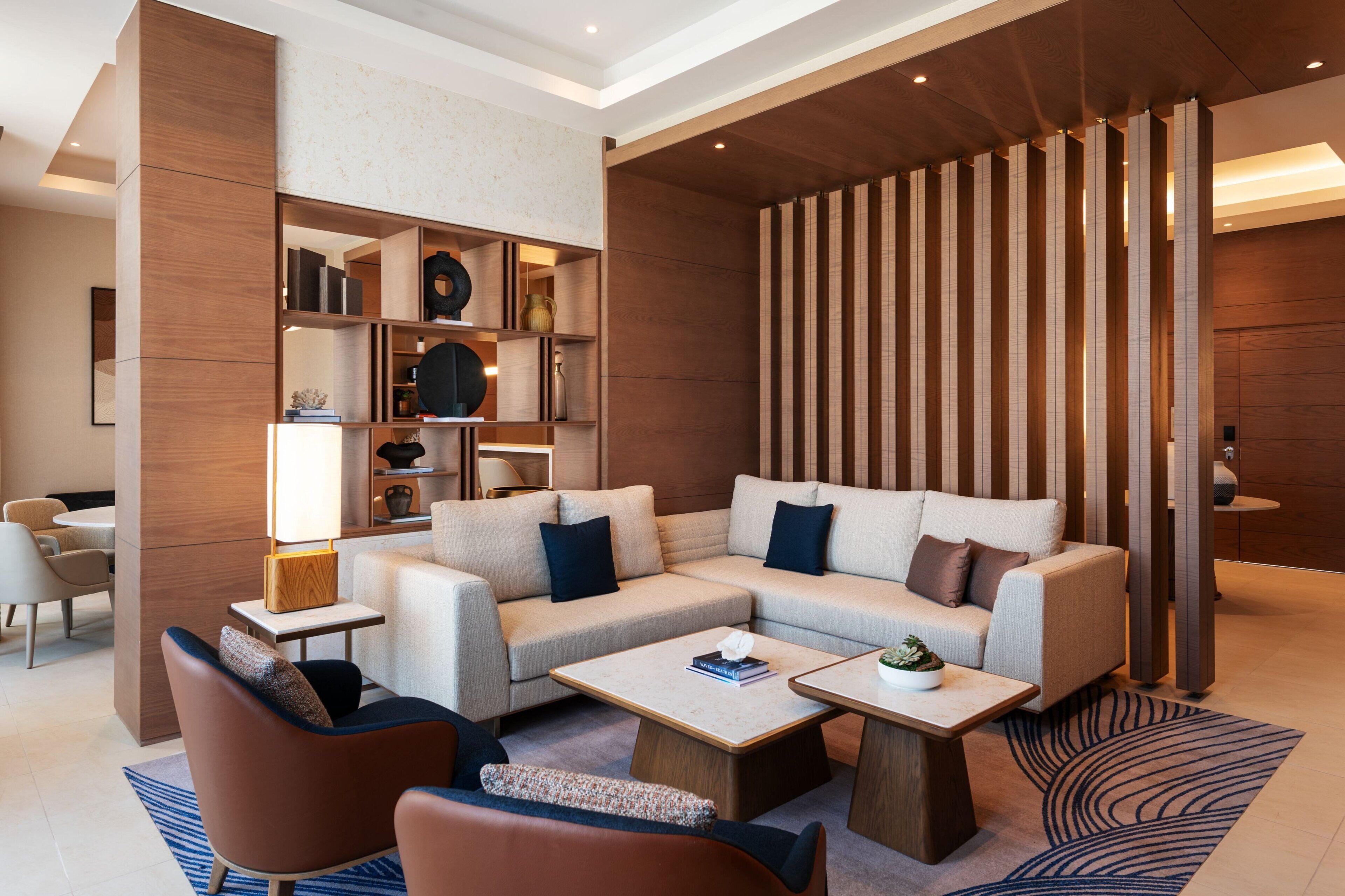 A modern living room with a sectional sofa, two coffee tables, and a decorative wall with vertical slats.