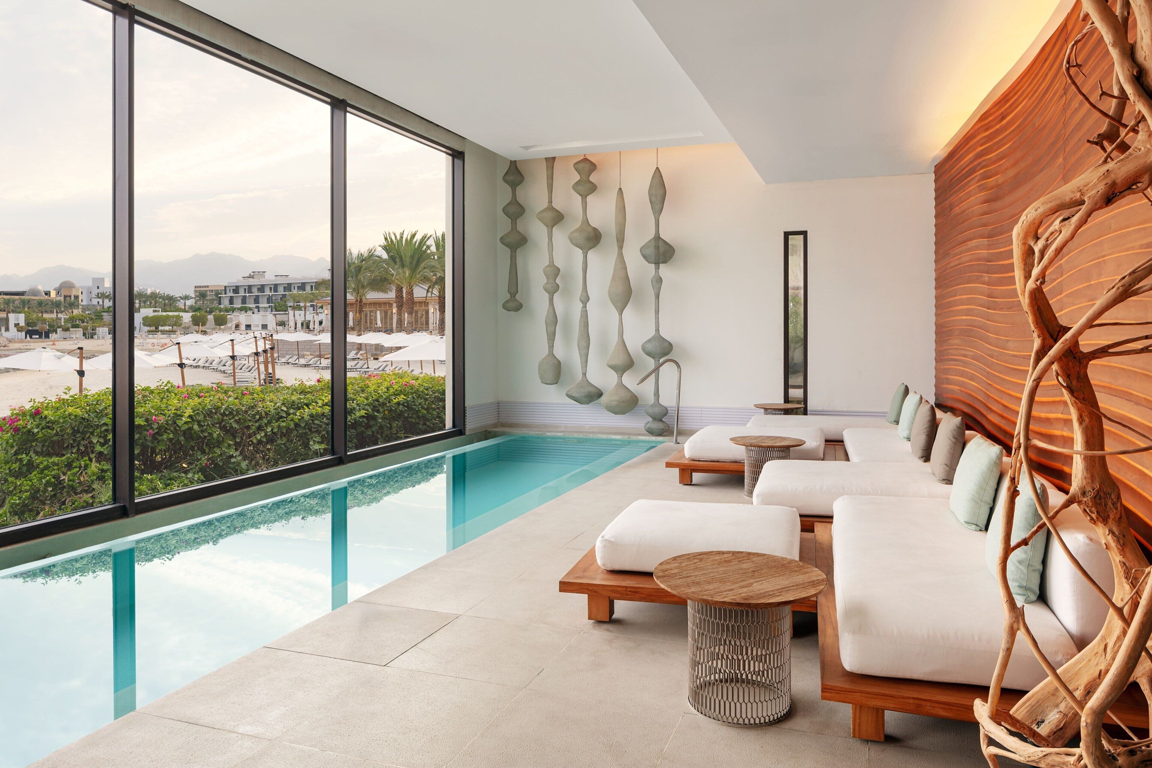 Ein modernes Hotelzimmer mit großem Fenster, Pool, Holzverkleidung und einer Sitzecke.