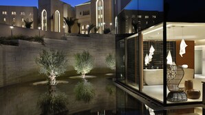Un hotel moderno con una piscina reflectante, un espacio exterior bien iluminado y vistas de la arquitectura del edificio.