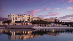 Un hotel grande con varias plantas, piscina y palmeras.