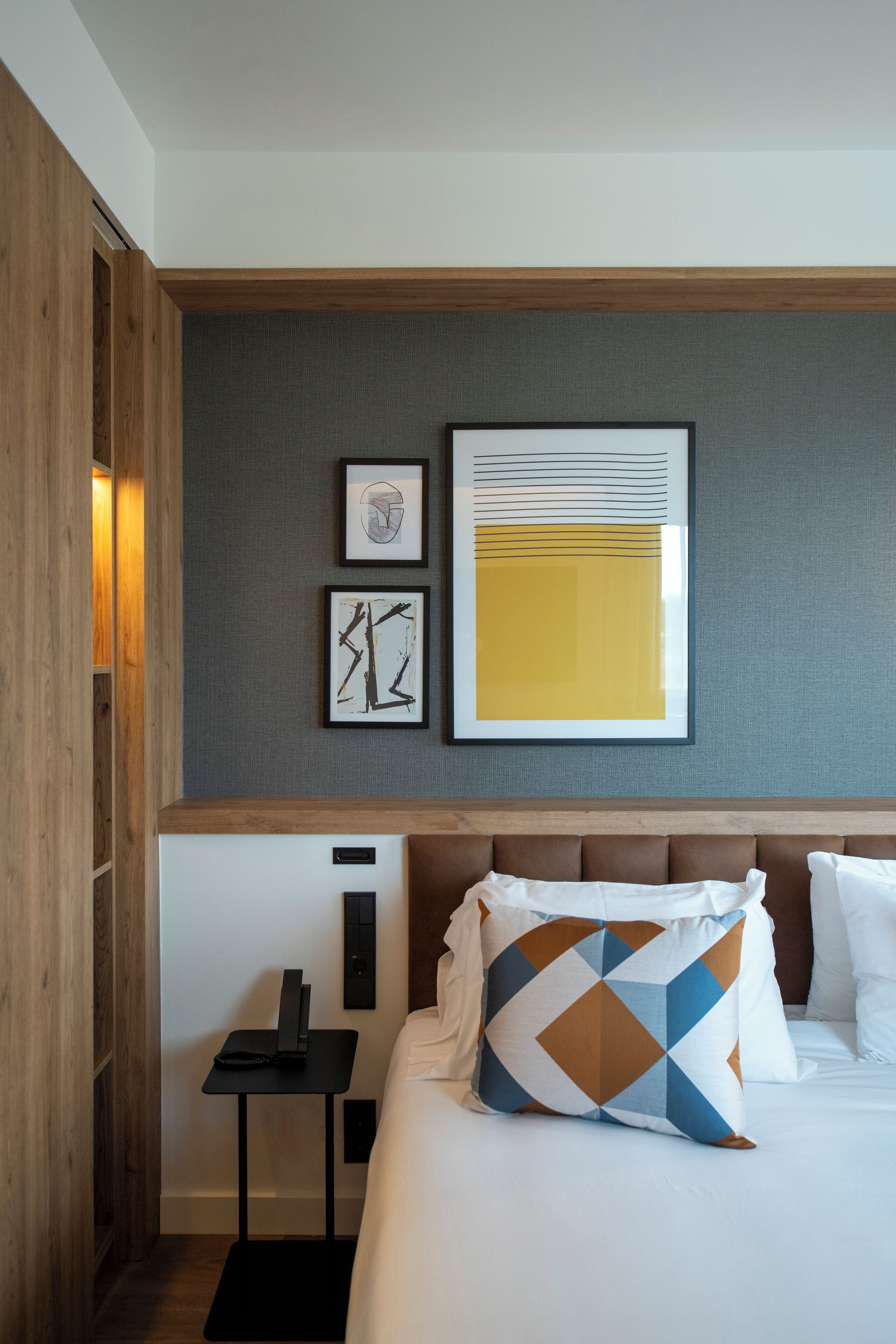 Una habitación de hotel con una cama, una mesita y una obra de arte en la pared.