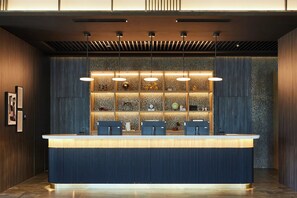 A reception desk with a modern design, featuring a blue and dark wood color scheme, and a decorative wall with various items and lighting above it.