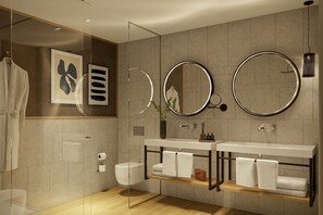 A modern bathroom with a glass shower enclosure, a double vanity with two sinks, and a large mirror above the vanity.