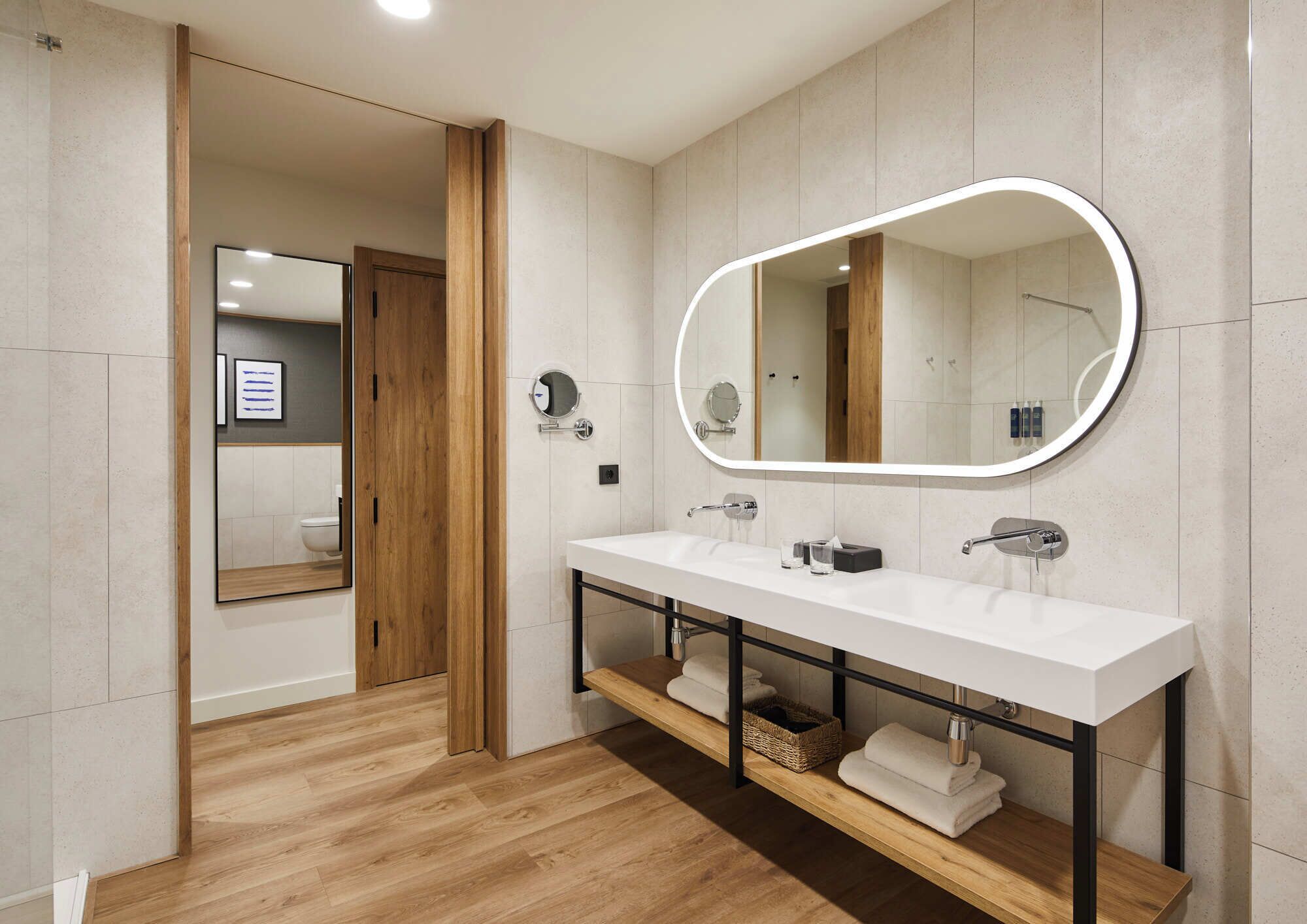 Un baño moderno con un lavabo blanco, dos espejos y un mueble de tocador de madera.