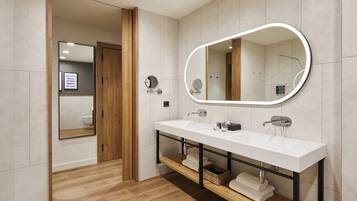 Un baño moderno con un lavabo blanco, dos espejos y un mueble de tocador de madera.