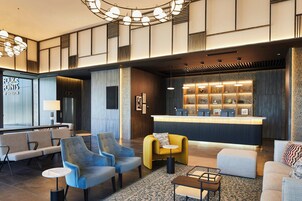 Um lobby moderno com áreas de estar, um balcão de recepção e uma parede decorativa com azulejos estampados.