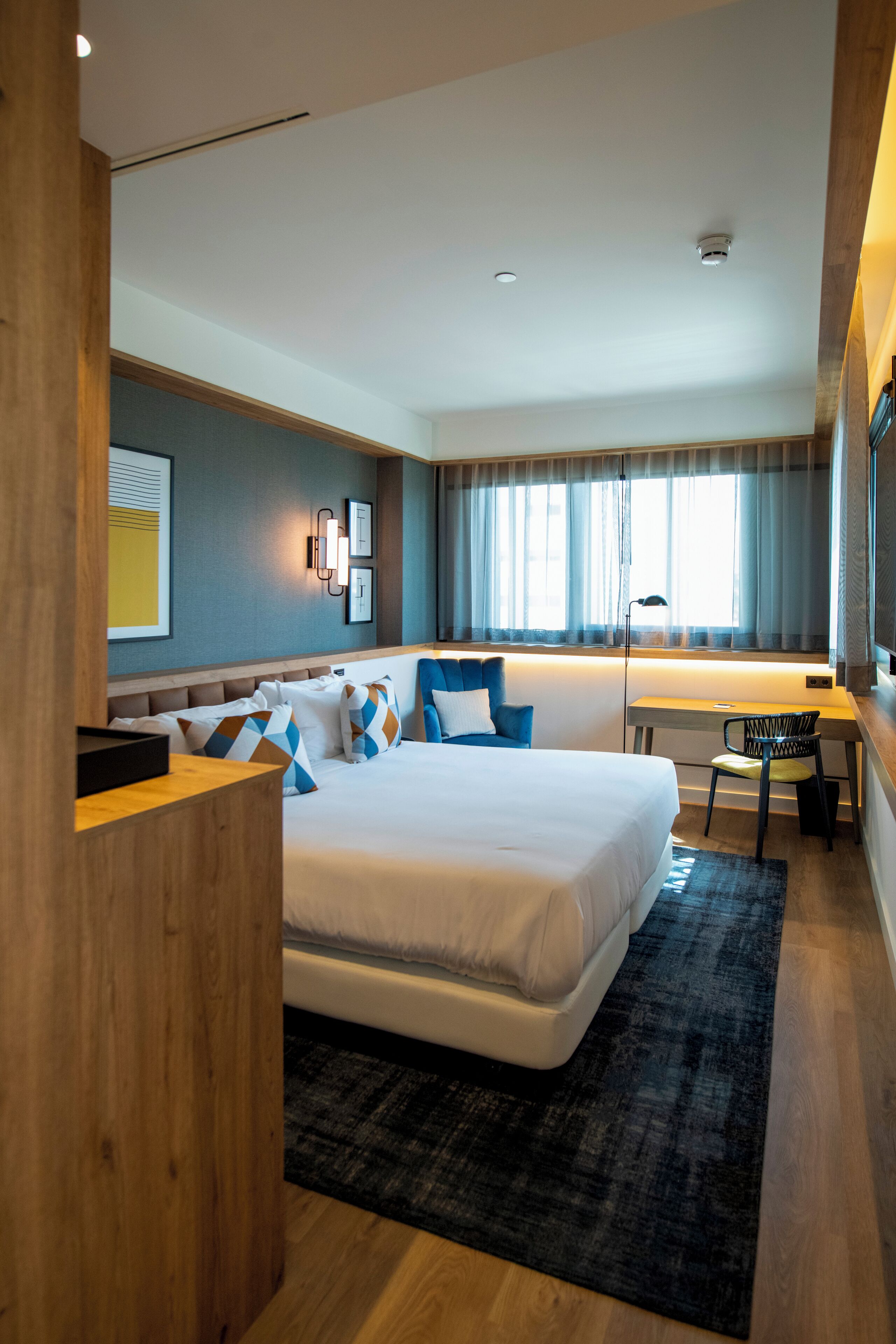 Ein modernes Hotelzimmer mit einem großen Bett, einem Schreibtisch und einem Stuhl.