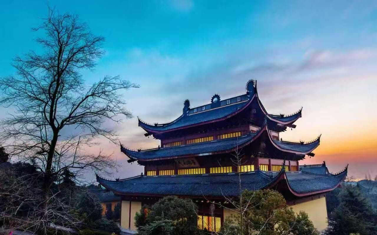 A traditional multi-tiered building with a complex roof structure, surrounded by trees.