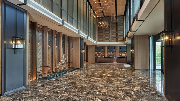 Un hall amplio con suelo de mármol pulido, grandes ventanales e iluminación moderna.