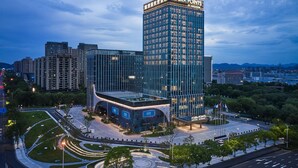 A modern hotel with a prominent 'Four Points' sign, surrounded by greenery and other buildings. - Four Points by Sheraton Huzhou (Huzhou)