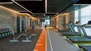 Un gimnasio moderno con cintas de correr, mancuernas, bancos y máquinas de pesas.