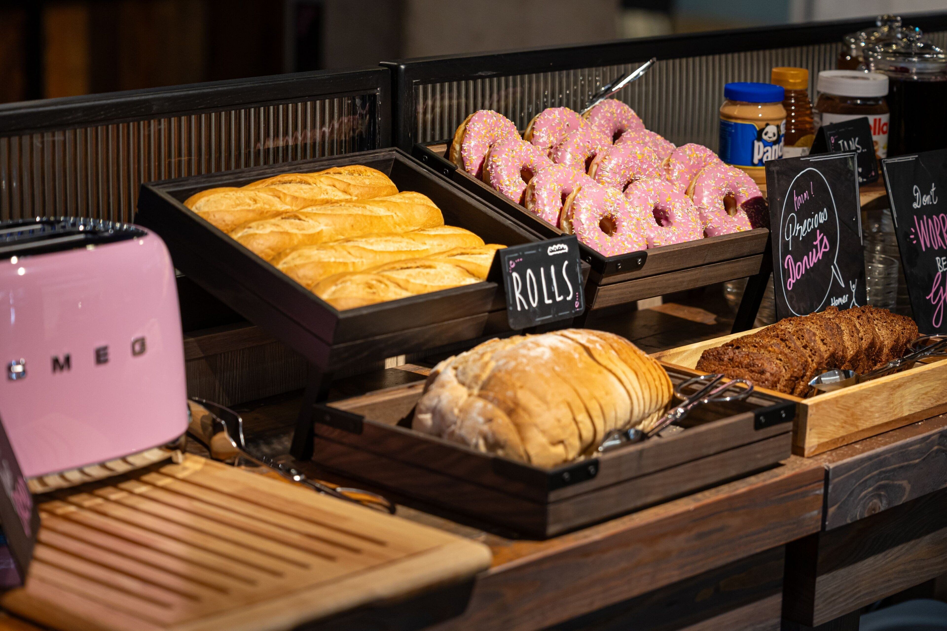 A bakery display with various baked goods including rolls, donuts, and a loaf of bread.