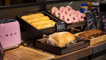 Una vitrina de panadería con diversas opciones de productos horneados, incluyendo bollos, rosquillas y una hogaza de pan.