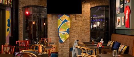 A restaurant with brick walls, wooden chairs, and tables.