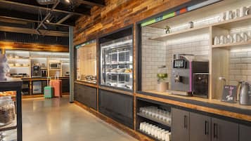 A modern kitchen area with stainless steel appliances, a coffee machine, and a display case with food items.