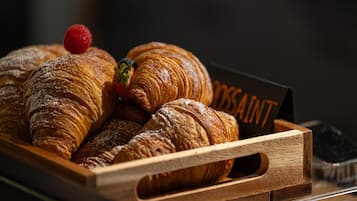 A wooden tray with several croissants and a strawberry.