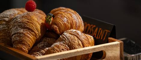 Ein Holztablett mit verschiedenen Croissants und einer Erdbeere.