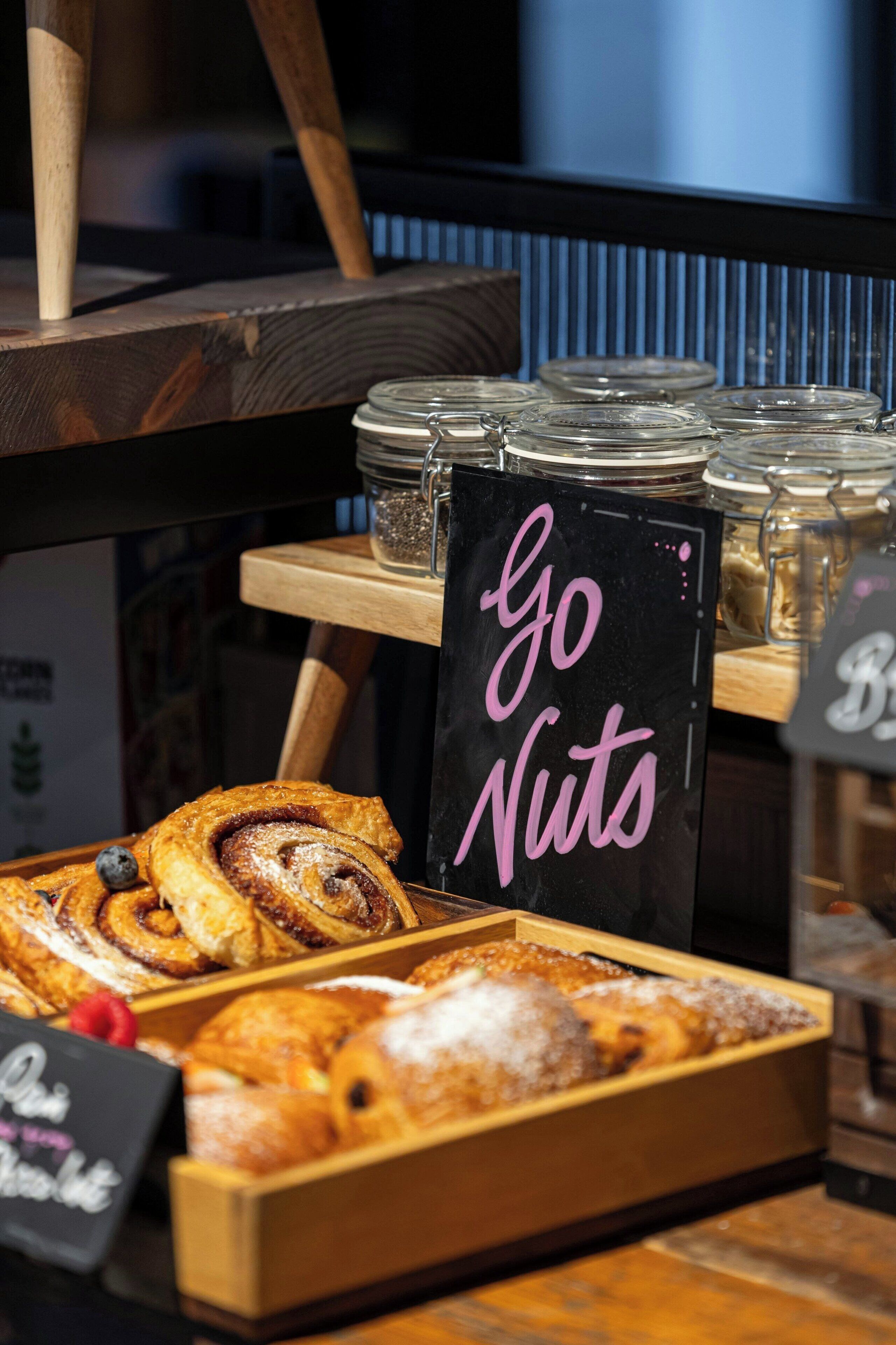 Mostrador de pastelería con productos de repostería y un letrero que dice 'Go Nuts'.