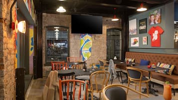 A cozy restaurant with brick walls, wooden chairs, and a large TV screen.