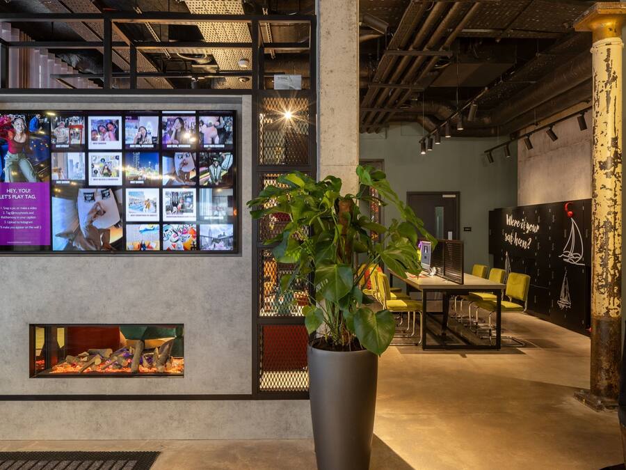 A modern interior with a large display wall, a potted plant, and a seating area.