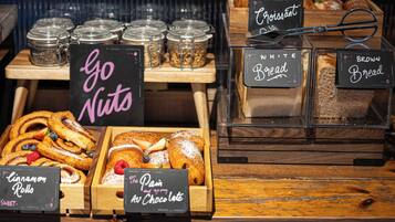 Mostrador de panadería con diversos productos horneados y letreros.