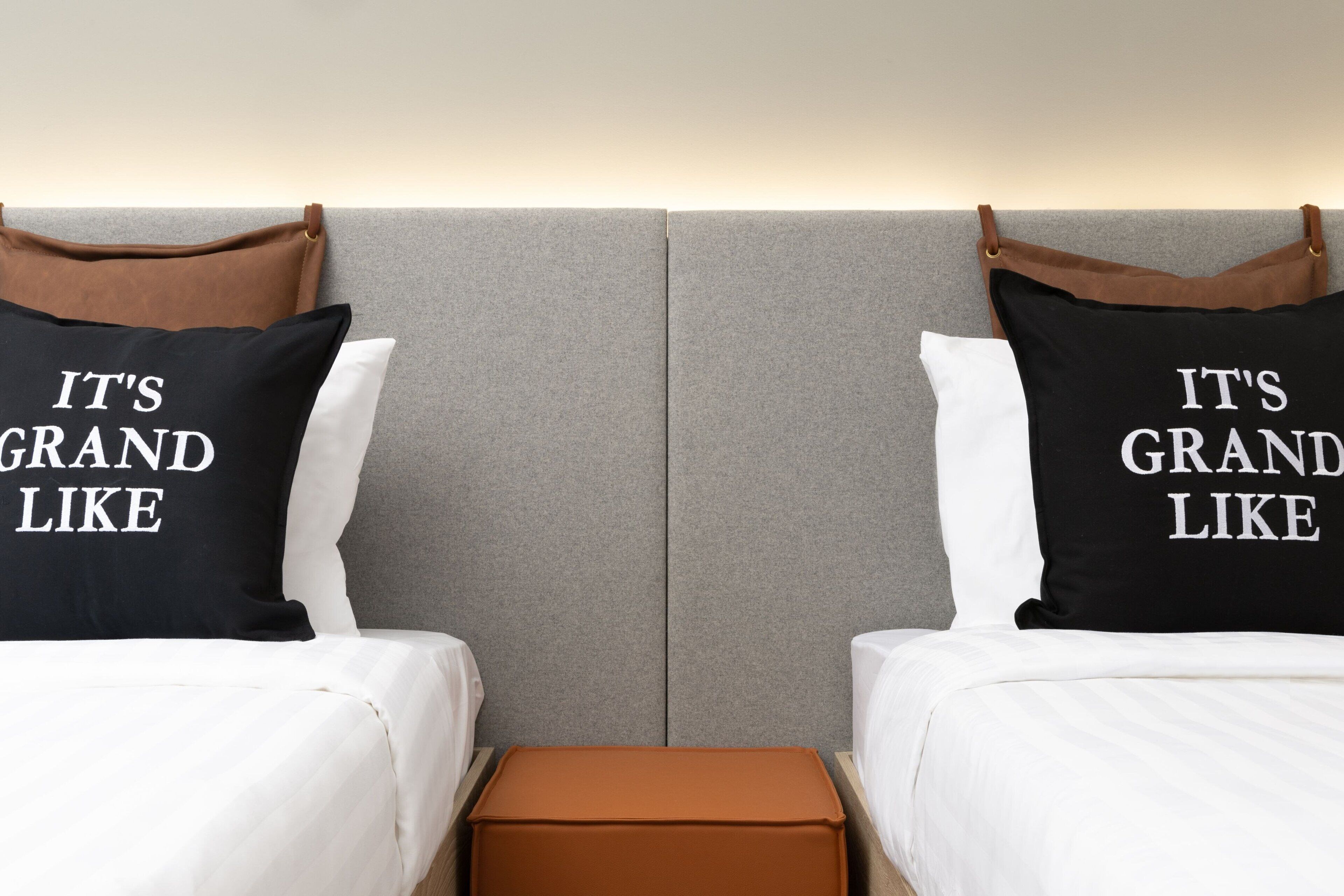 Una habitación de hotel con dos camas, cada una con un almohadón que dice "IT'S GRAND LIKE".
