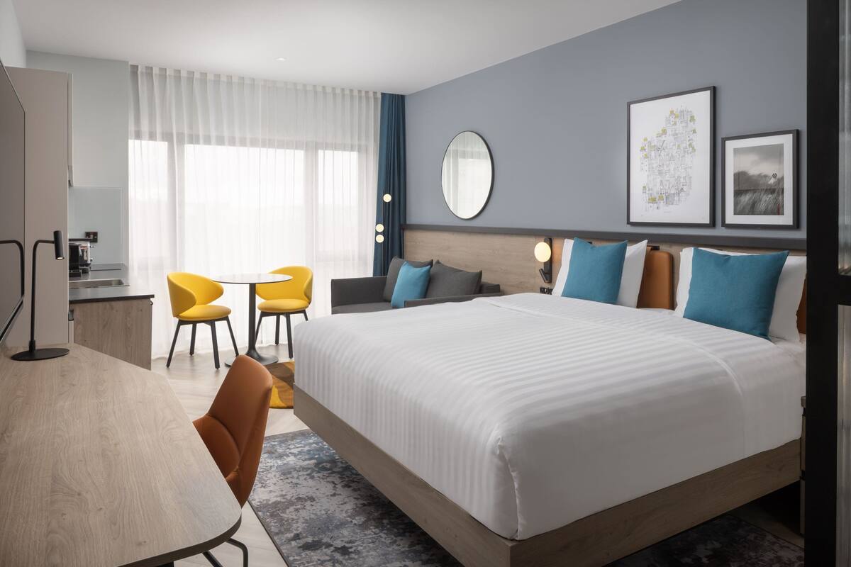 Ein modernes Hotelzimmer mit einem großen Bett, einem Schreibtisch und zwei Stühlen.