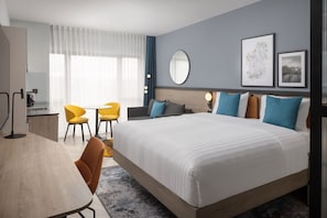Una habitación de hotel moderna con una cama grande, un escritorio y dos sillas.