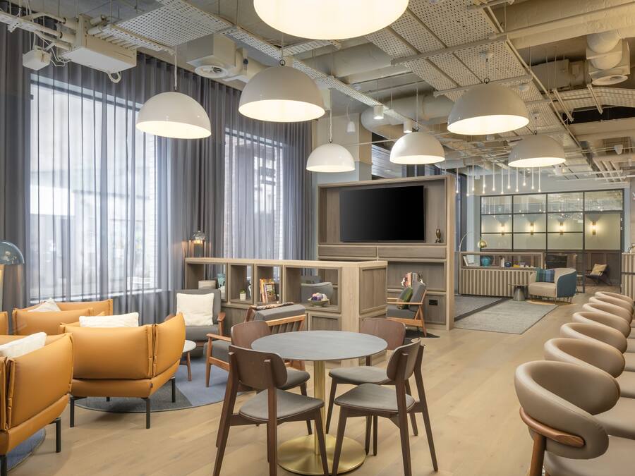 Un moderno vestíbulo de hotel con una mesa de comedor redonda, sofás y una zona de bar.