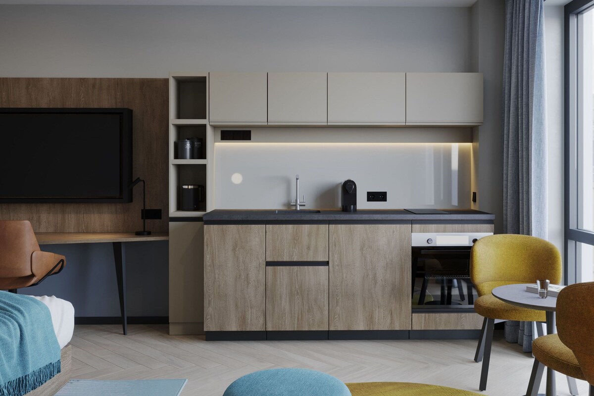 A modern kitchen with a built-in oven, a coffee machine, and a dining area with a round table and two chairs.